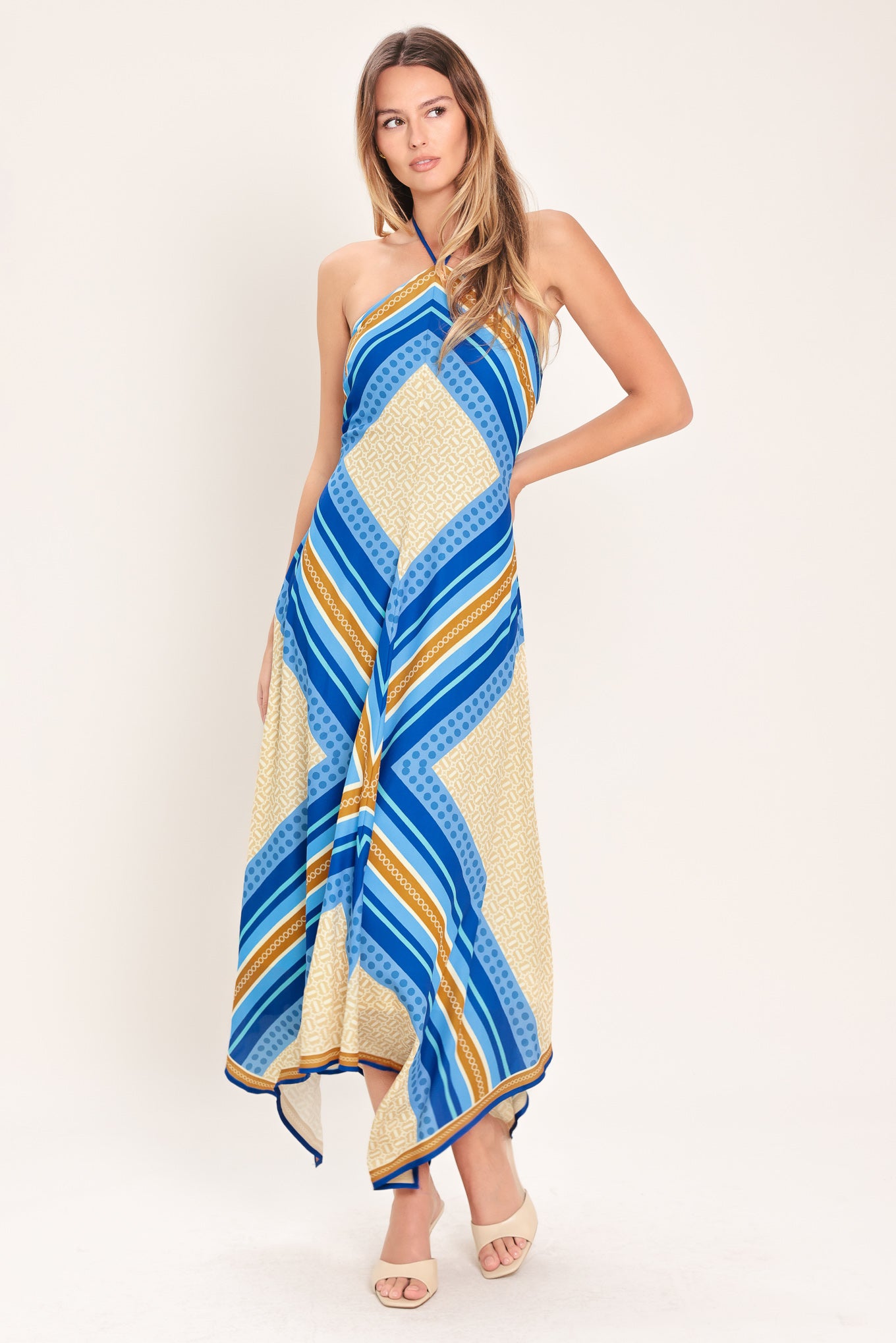 Woman wearing a blue and gold midi dress featuring halter neckline with tie, hanky hem and back zipper closure | Flying Tomato