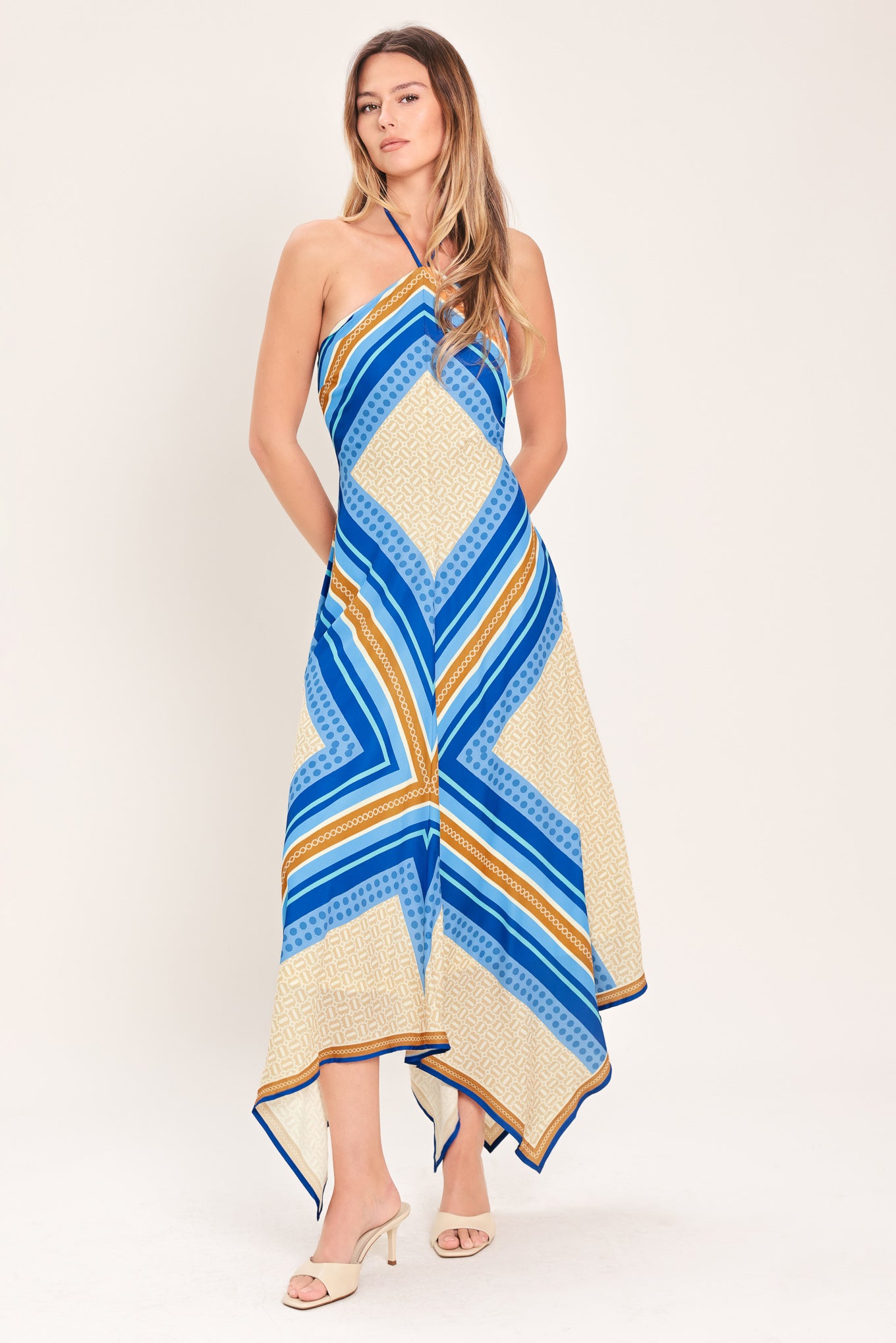 Woman wearing a blue and gold midi dress featuring halter neckline with tie, hanky hem and back zipper closure | Flying Tomato