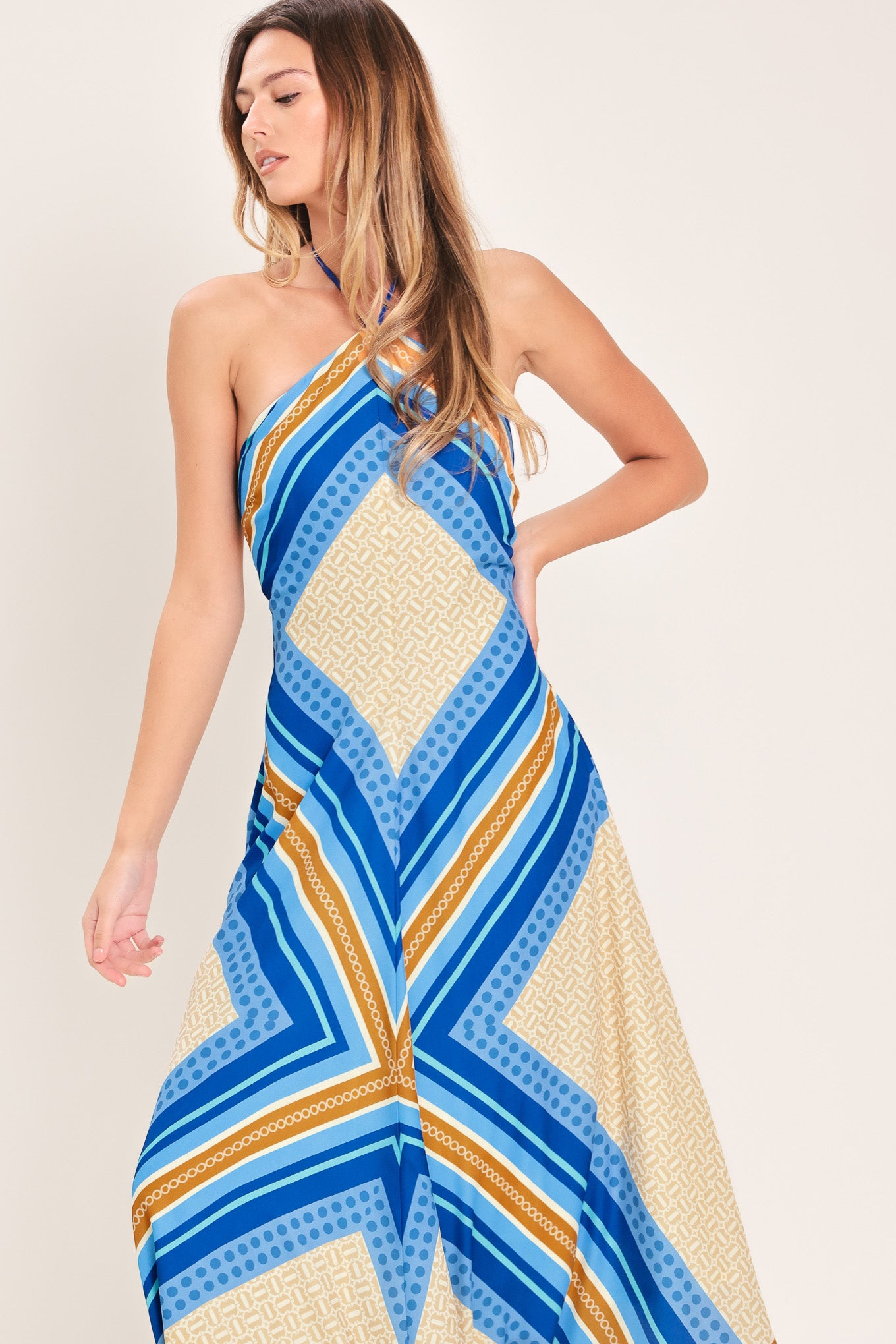 Woman wearing a blue and gold midi dress featuring halter neckline with tie, hanky hem and back zipper closure | Flying Tomato