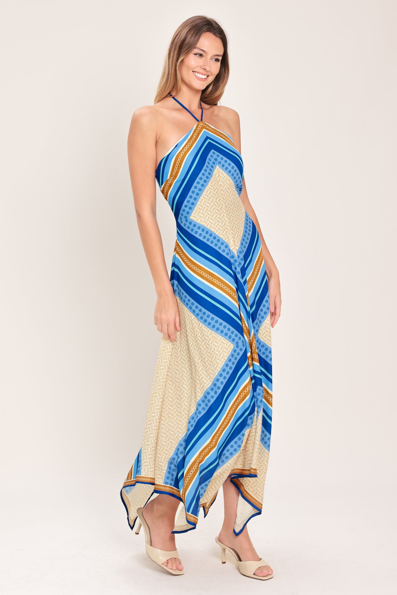 Woman wearing a blue and gold midi dress featuring halter neckline with tie, hanky hem and back zipper closure | Flying Tomato