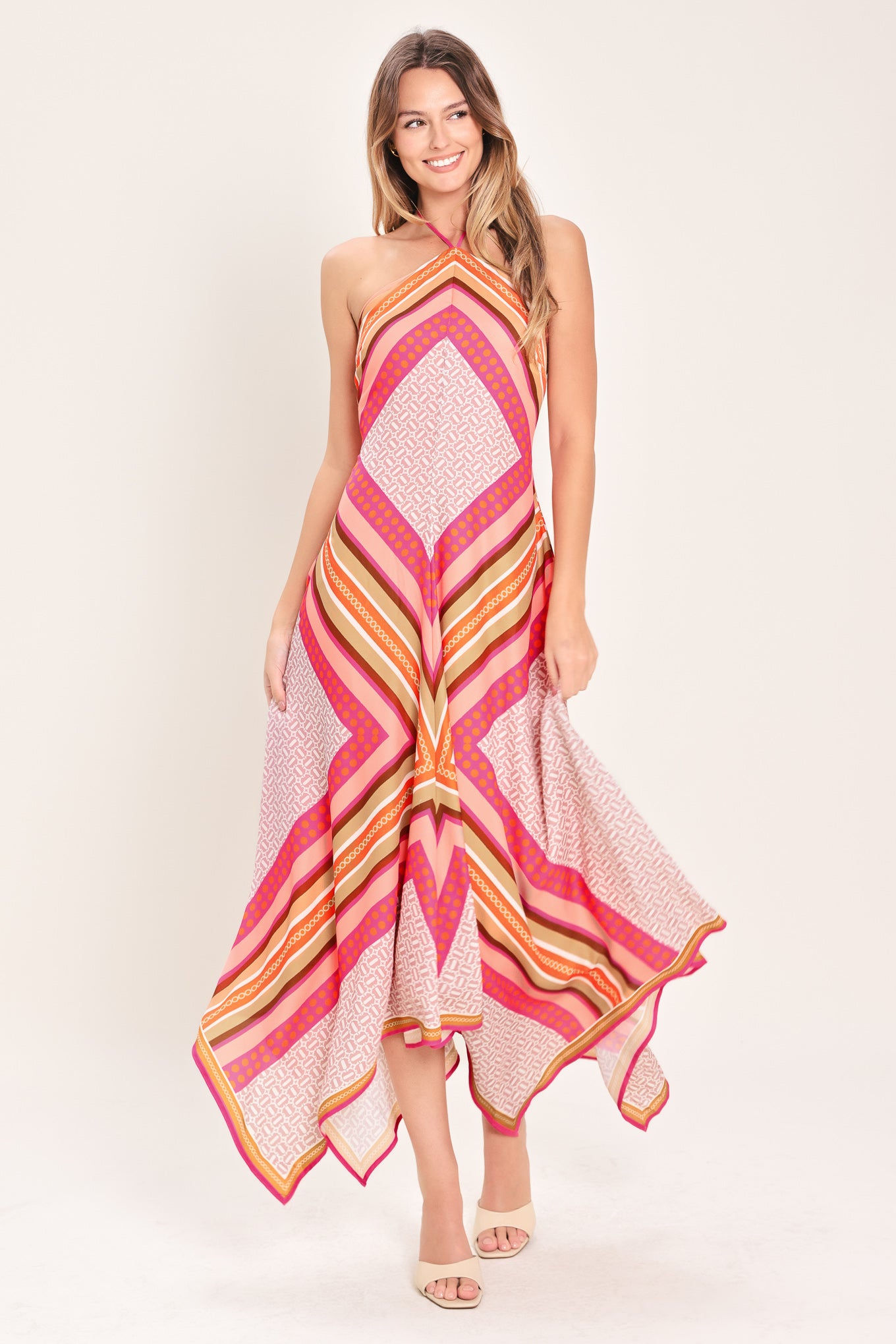 Woman wearing a pink and gold midi dress featuring halter neckline with tie, hanky hem and back zipper closure | Flying Tomato