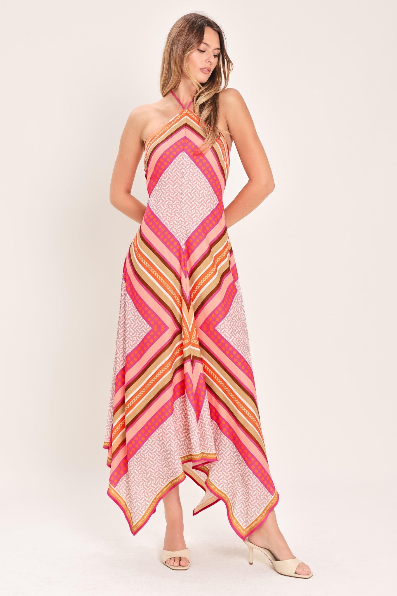 Woman wearing a pink and gold midi dress featuring halter neckline with tie, hanky hem and back zipper closure | Flying Tomato