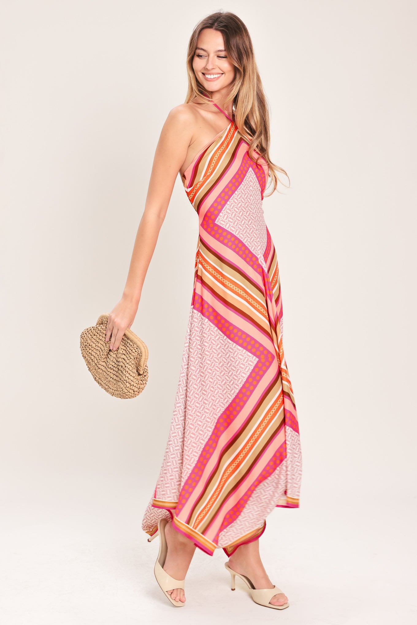 Woman wearing a pink and gold midi dress featuring halter neckline with tie, hanky hem and back zipper closure | Flying Tomato