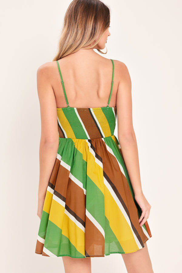 Woman wearing a green, brown, and yellow mini dress with straps, waist yoke, full skirt and smocked back bodice | Flying Tomato