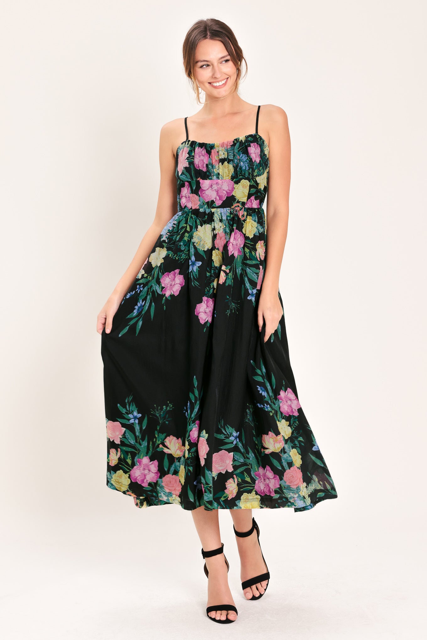 Woman wearing a black floral midi dress featuring straight neckline with shirred bust, straps, full skirt and back zipper closure | Flying Tomato