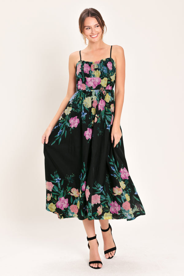 Woman wearing a black floral midi dress featuring straight neckline with shirred bust, straps, full skirt and back zipper closure | Flying Tomato