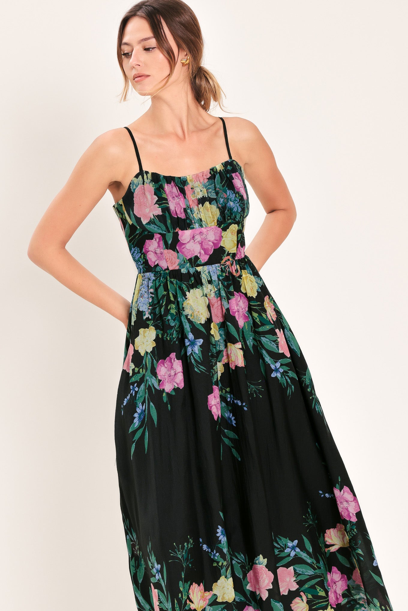 Woman wearing a black floral midi dress featuring straight neckline with shirred bust, straps, full skirt and back zipper closure | Flying Tomato