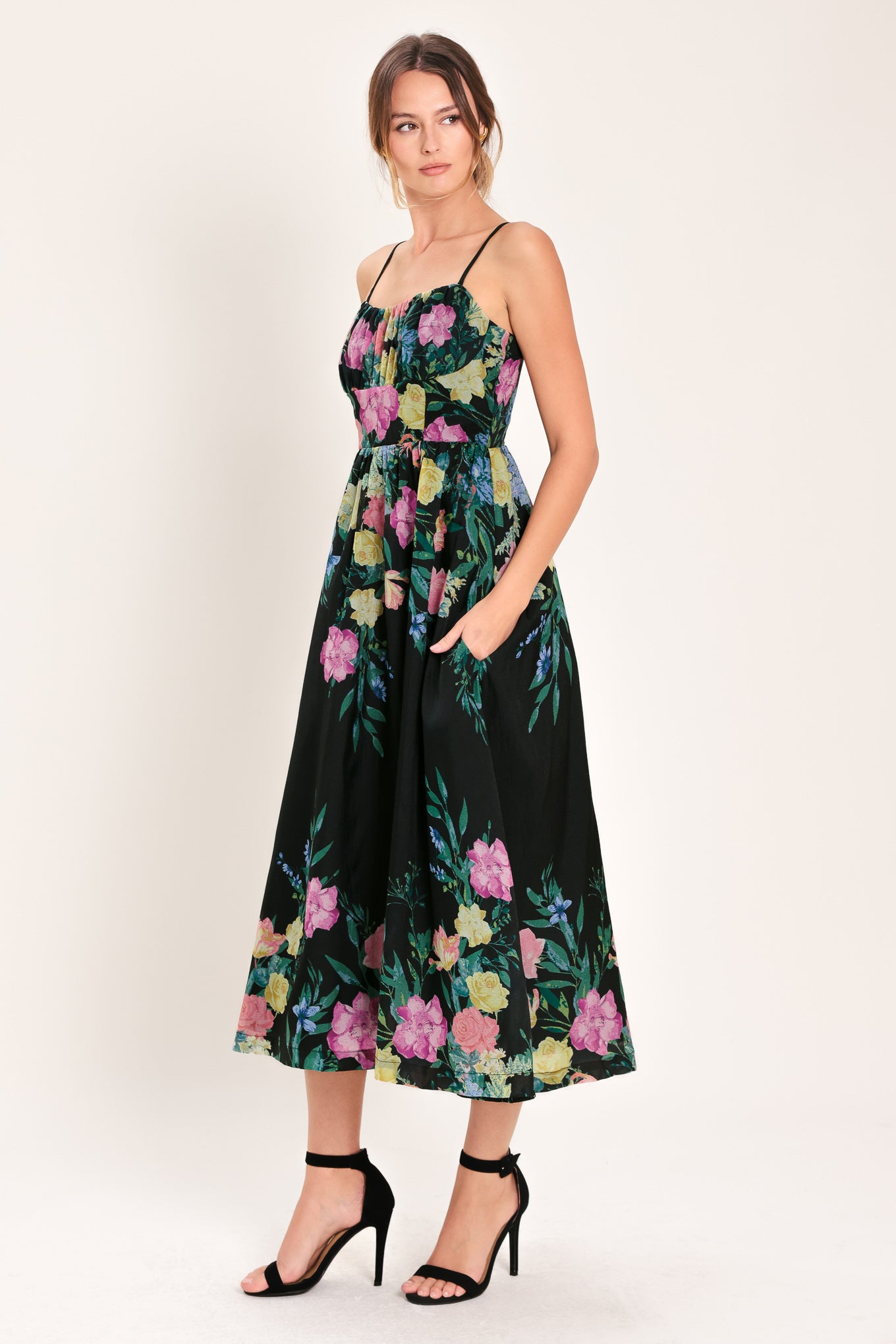 Woman wearing a black floral midi dress featuring straight neckline with shirred bust, straps, full skirt and back zipper closure | Flying Tomato