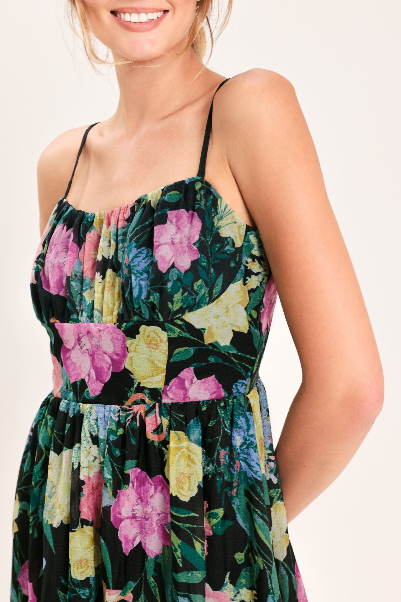 Woman wearing a black floral midi dress featuring straight neckline with shirred bust, straps, full skirt and back zipper closure | Flying Tomato