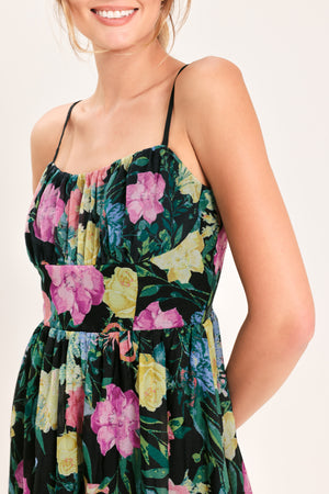 Woman wearing a black floral midi dress featuring straight neckline with shirred bust, straps, full skirt and back zipper closure | Flying Tomato