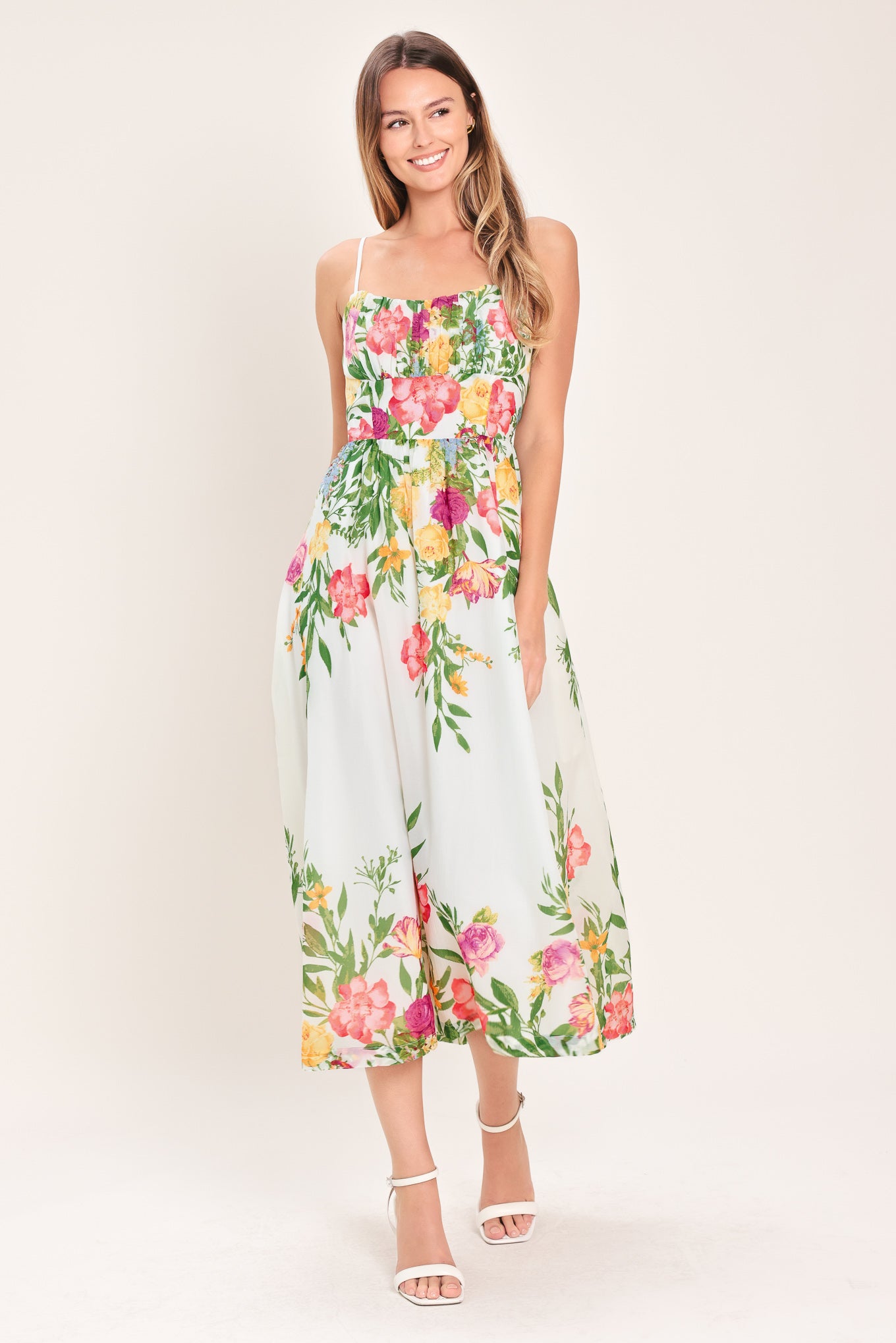 Woman wearing a white floral midi dress featuring straight neckline with shirred bust, straps, full skirt and back zipper closure | Flying Tomato