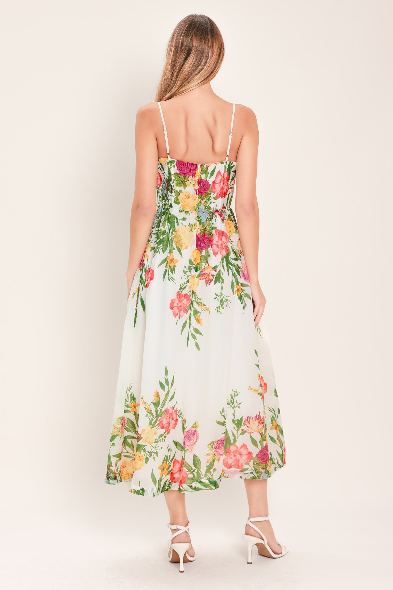 Woman wearing a white floral midi dress featuring straight neckline with shirred bust, straps, full skirt and back zipper closure | Flying Tomato
