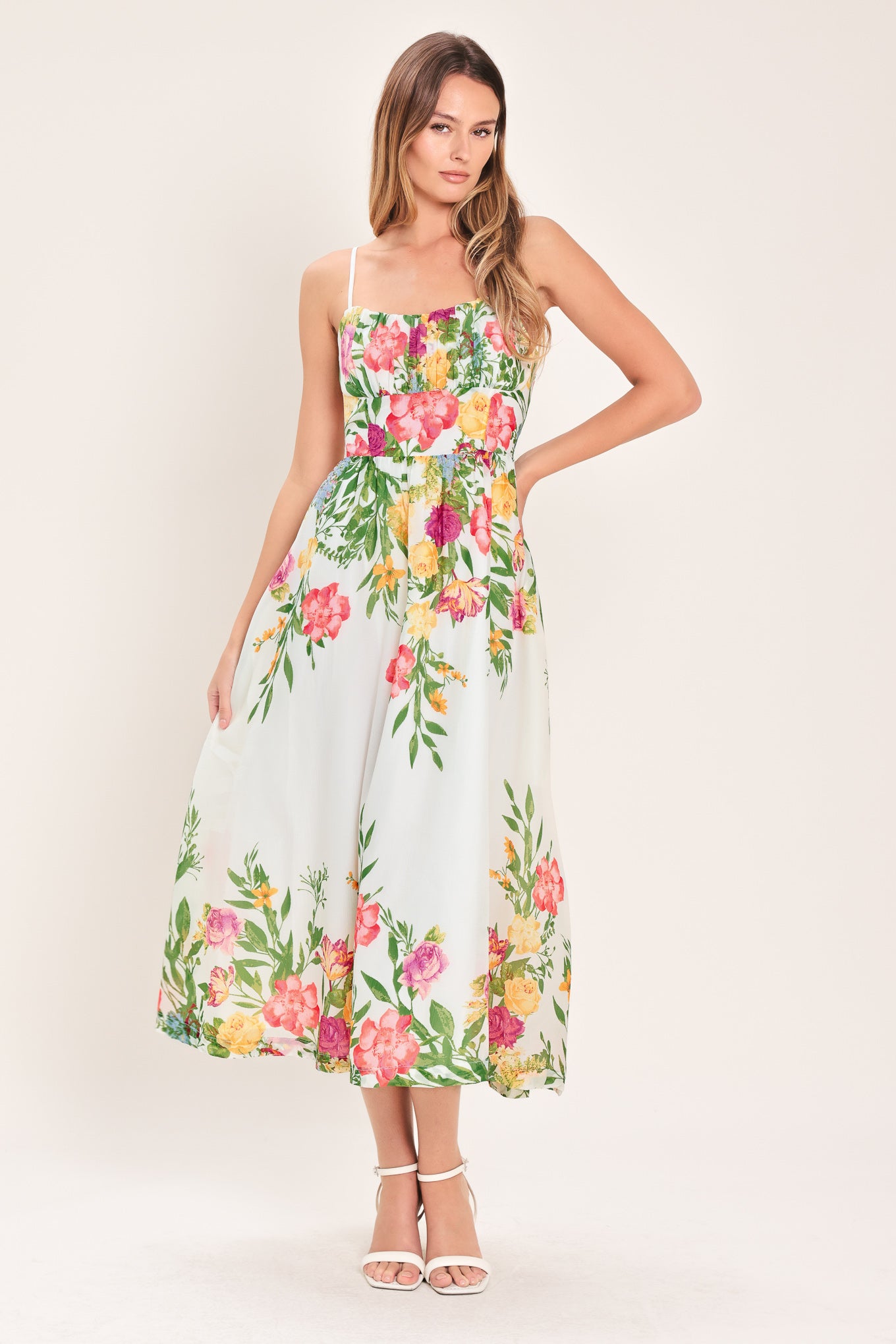Woman wearing a white floral midi dress featuring straight neckline with shirred bust, straps, full skirt and back zipper closure | Flying Tomato