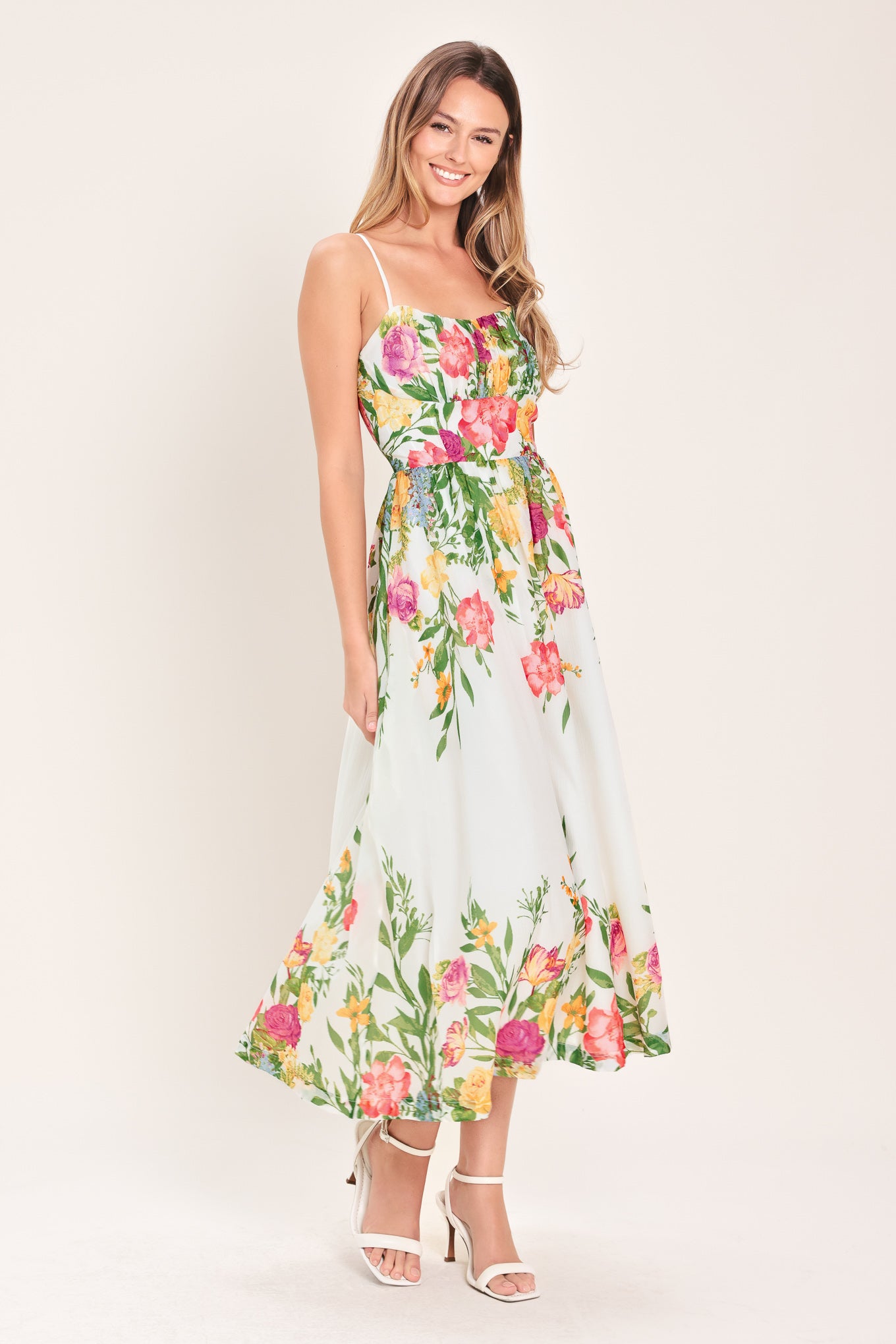 Woman wearing a white floral midi dress featuring straight neckline with shirred bust, straps, full skirt and back zipper closure | Flying Tomato