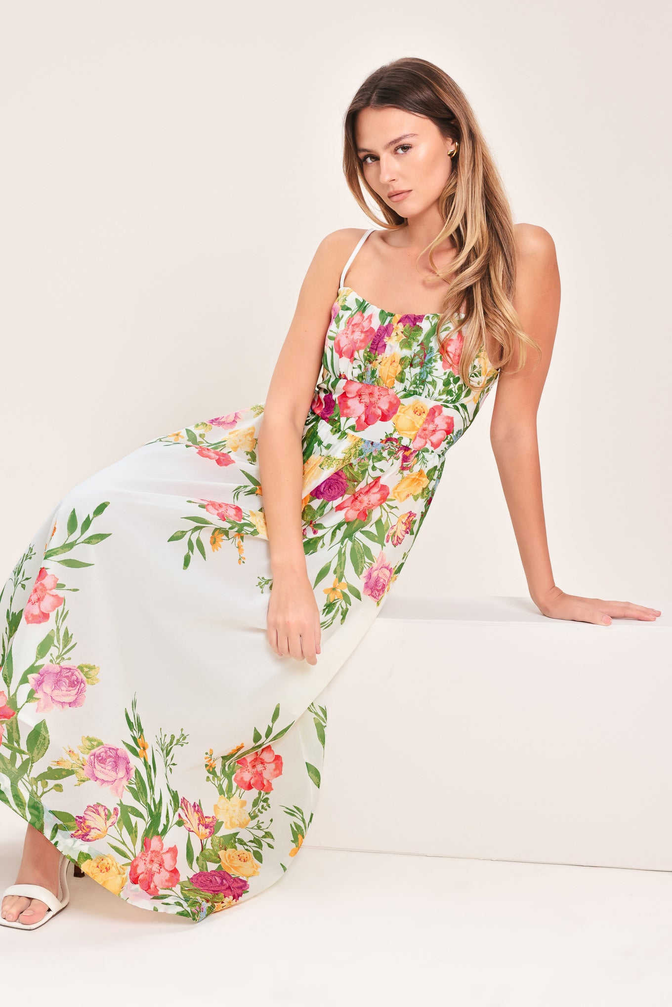 Woman wearing a white floral midi dress featuring straight neckline with shirred bust, straps, full skirt and back zipper closure | Flying Tomato