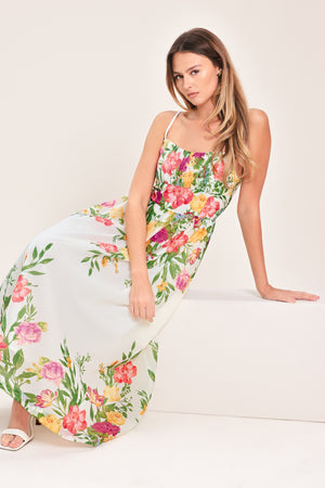 Woman wearing a white floral midi dress featuring straight neckline with shirred bust, straps, full skirt and back zipper closure | Flying Tomato