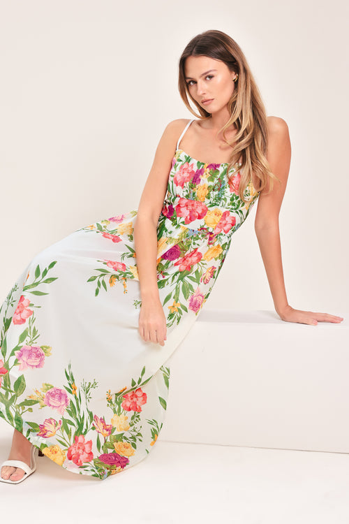 Woman wearing a white floral midi dress featuring straight neckline with shirred bust, straps, full skirt and back zipper closure | Flying Tomato