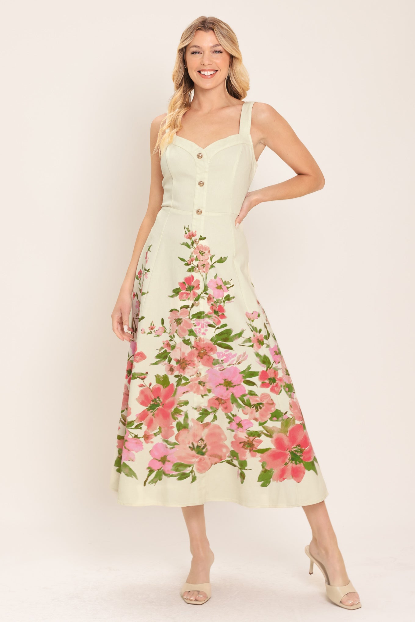 Woman wearing an ivory midi dress with pink floral pattern featuring sweetheart neckline, straps, button down detail, circle skirt and back zipper closure | Flying Tomato