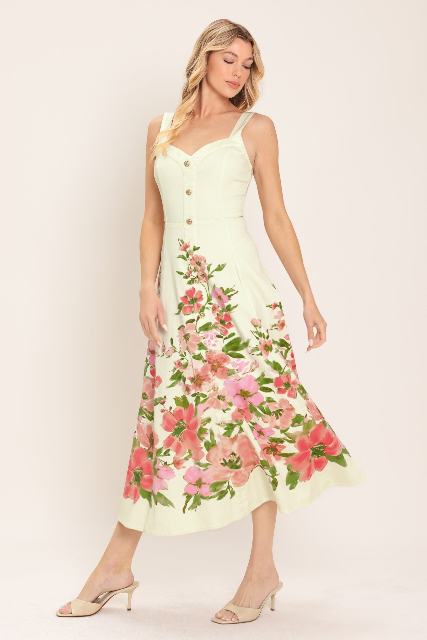 Woman wearing an ivory midi dress with pink floral pattern featuring sweetheart neckline, straps, button down detail, circle skirt and back zipper closure | Flying Tomato