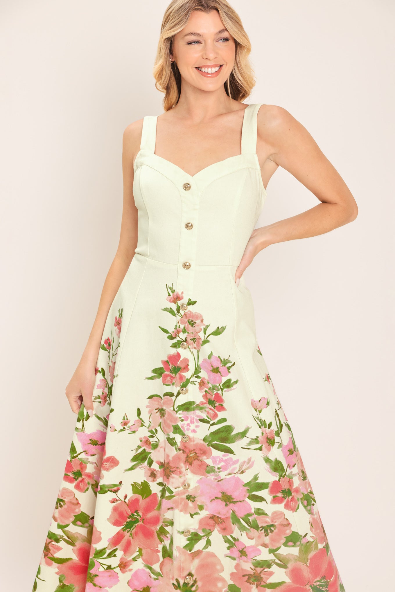 Woman wearing an ivory midi dress with pink floral pattern featuring sweetheart neckline, straps, button down detail, circle skirt and back zipper closure | Flying Tomato