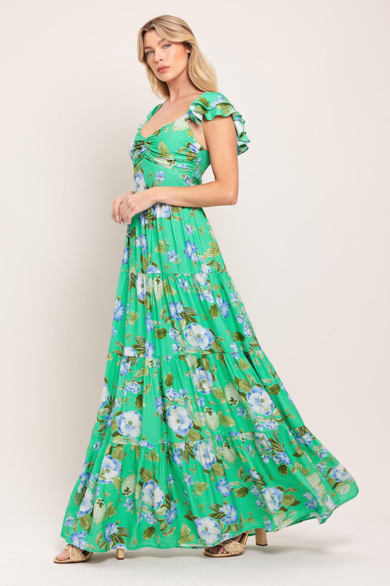 Woman wearing a green and blue floral maxi dress featuring sweetheart neckline, shirred bust, double ruffle sleeve, tier skirt and smocked back bodice | Flying Tomato