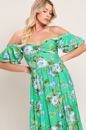 Woman wearing a green and blue floral maxi dress featuring sweetheart neckline, shirred bust, double ruffle sleeve, tier skirt and smocked back bodice | Flying Tomato