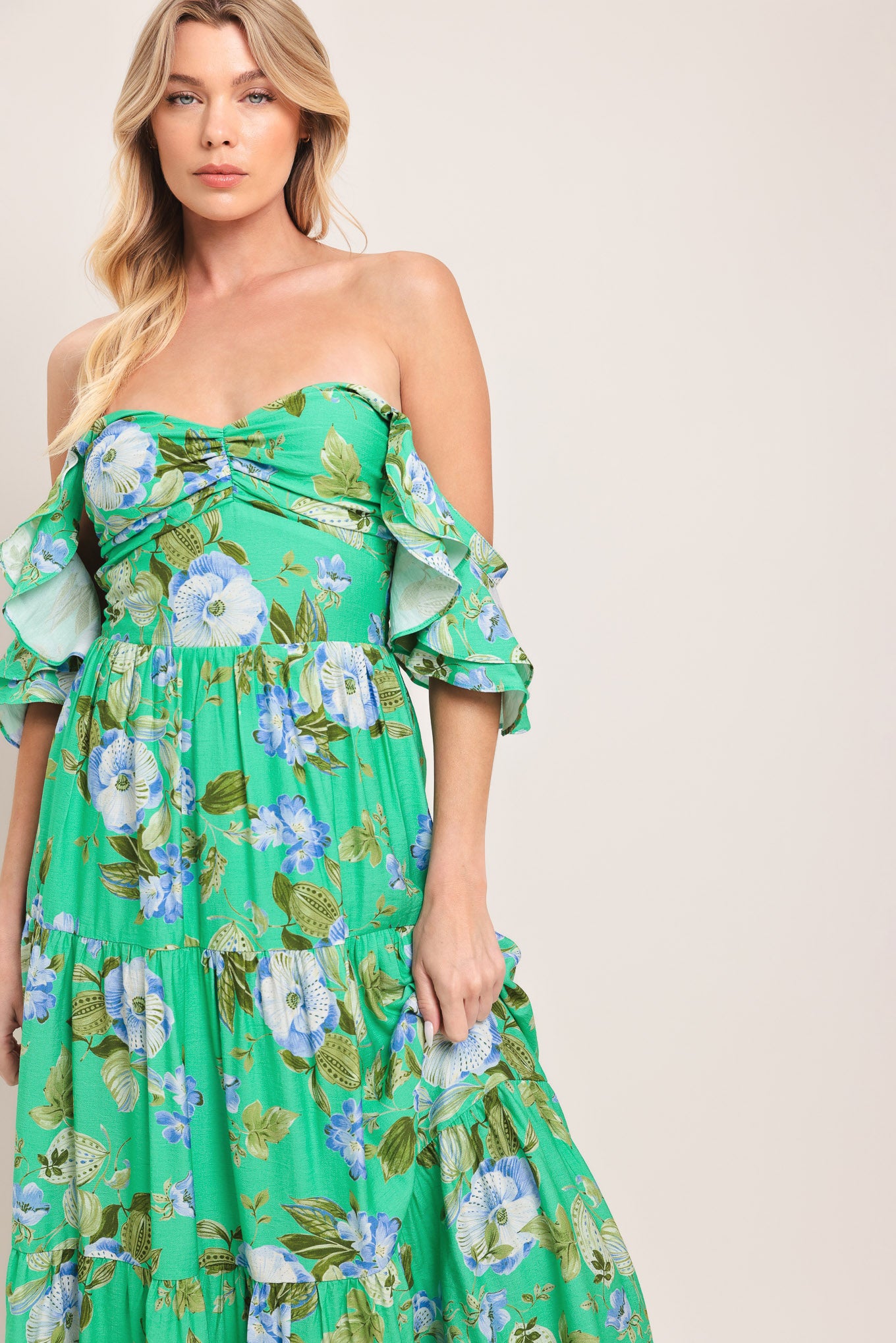 Woman wearing a green and blue floral maxi dress featuring sweetheart neckline, shirred bust, double ruffle sleeve, tier skirt and smocked back bodice | Flying Tomato