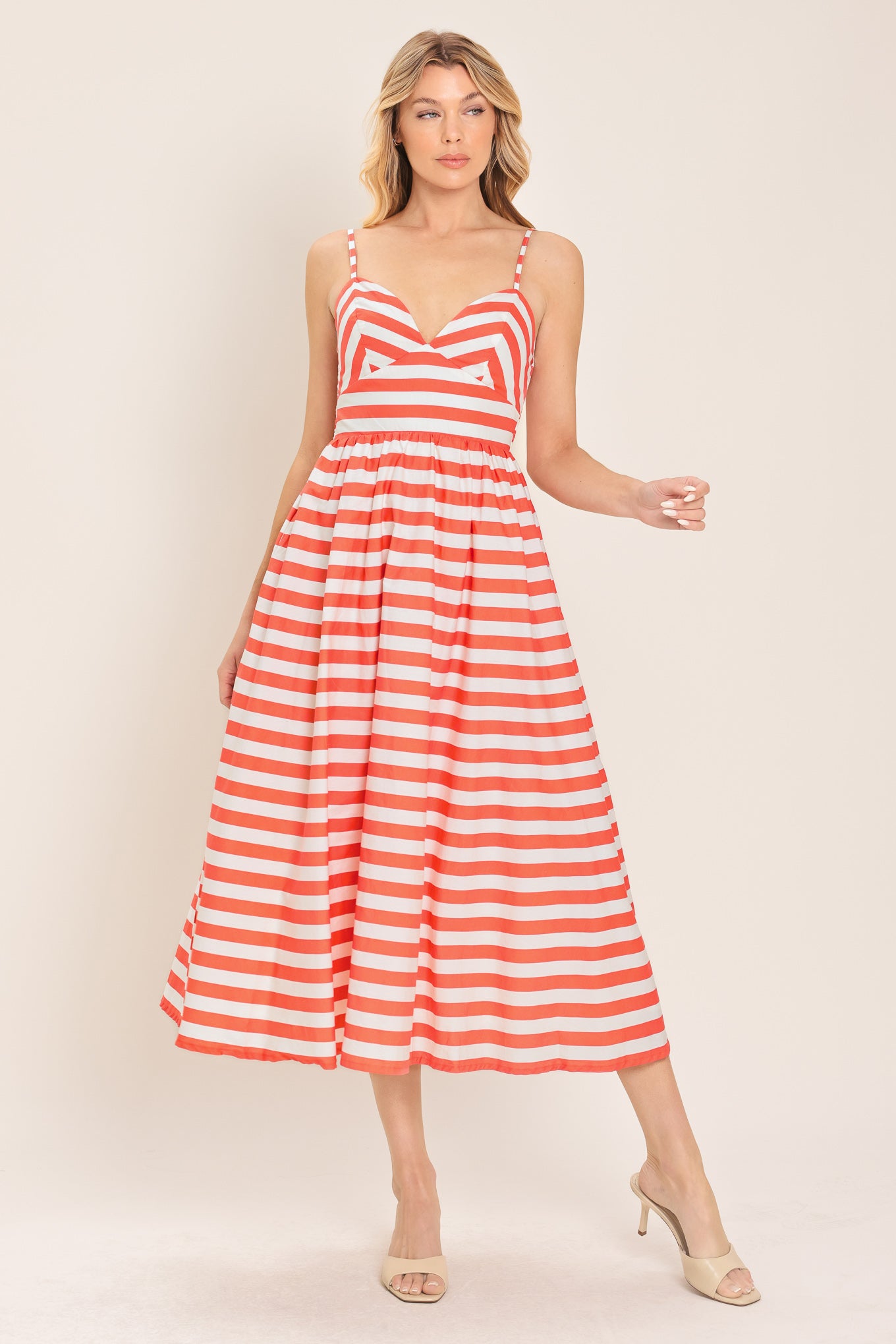 Woman wearing a coral and white striped midi dress featuring cami top, straps, full skirt and smocked back bodice | Flying Tomato