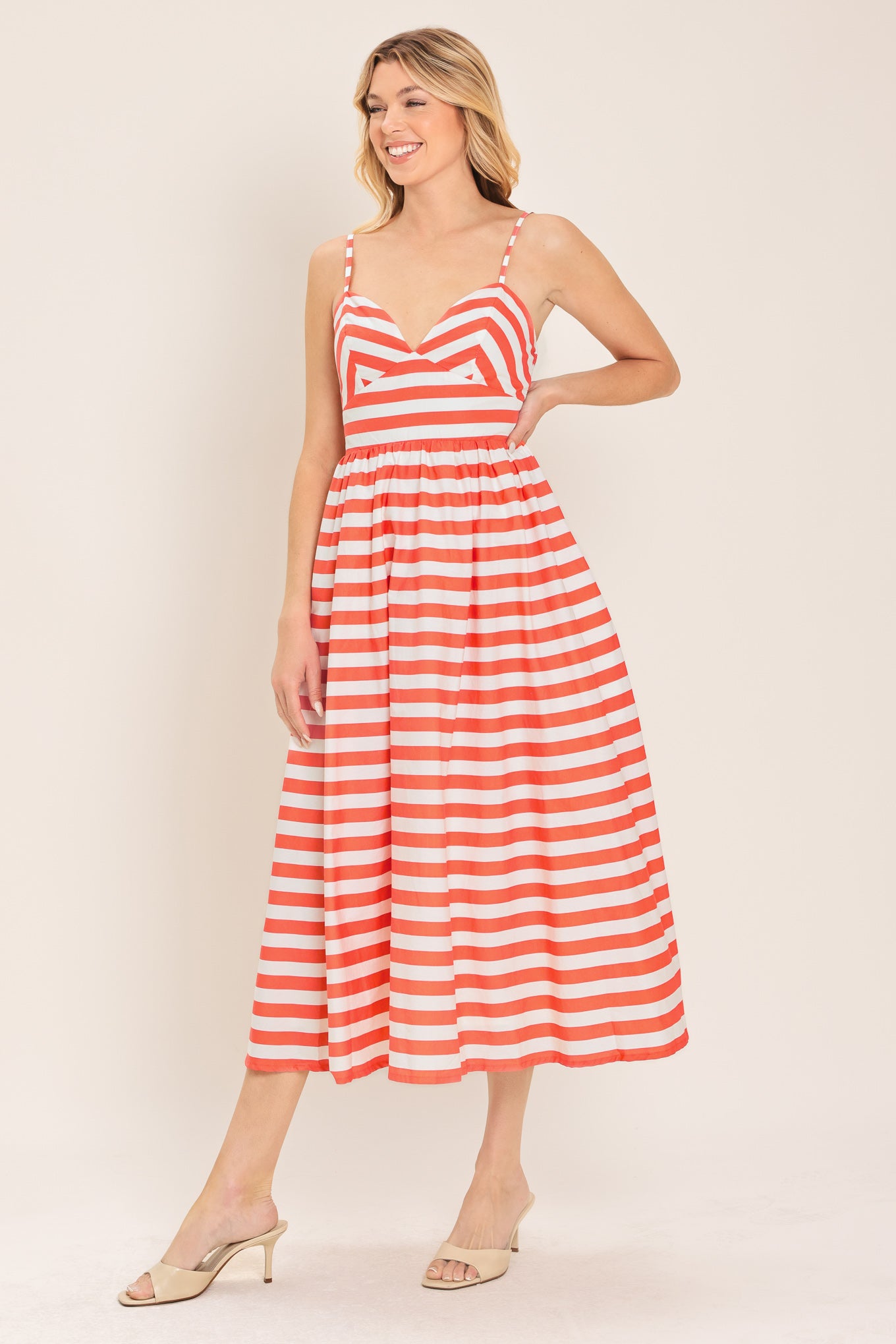Woman wearing a coral and white striped midi dress featuring cami top, straps, full skirt and smocked back bodice | Flying Tomato