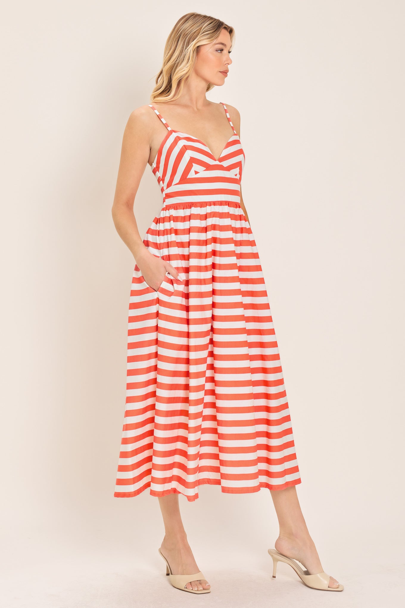 Woman wearing a coral and white striped midi dress featuring cami top, straps, full skirt and smocked back bodice | Flying Tomato