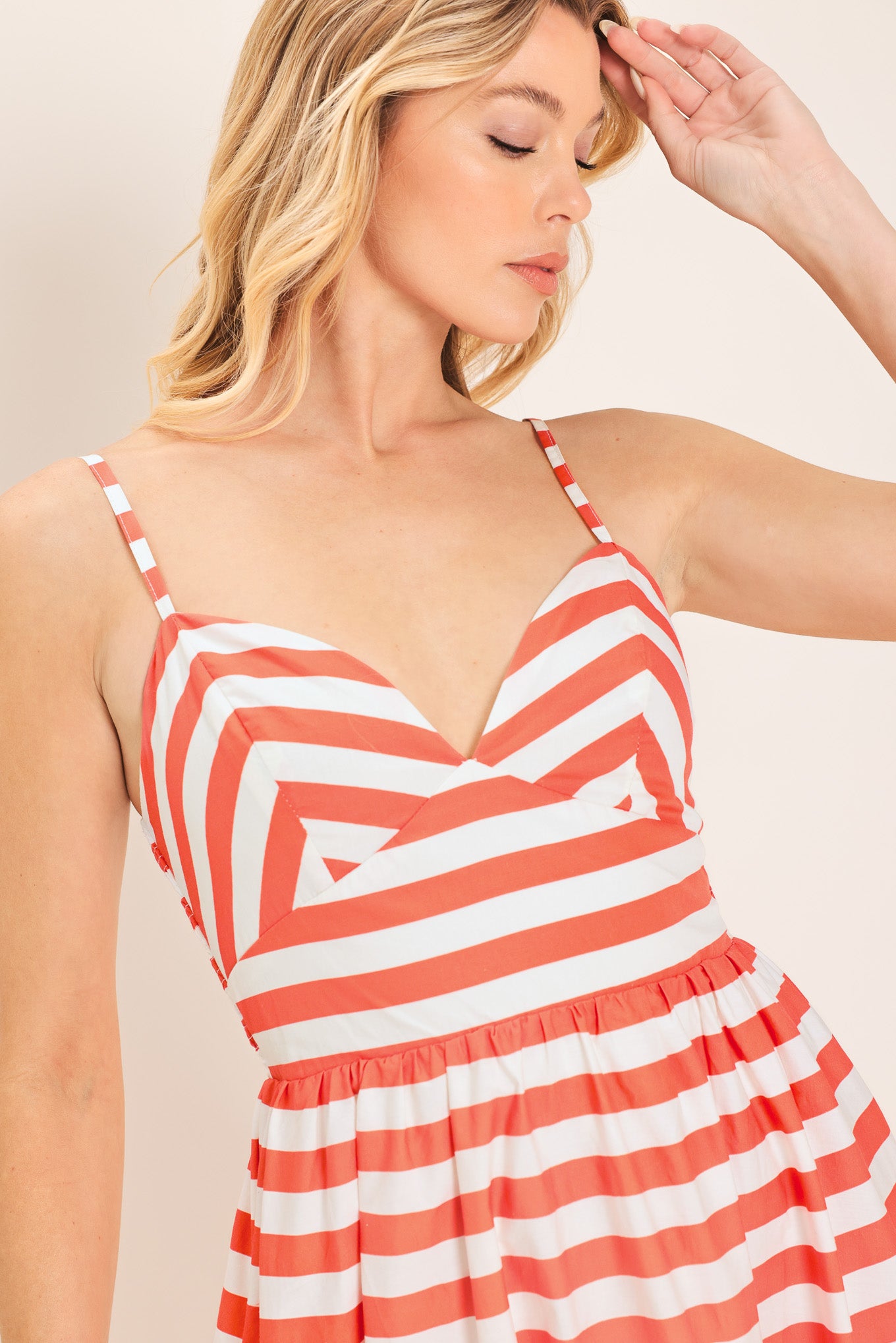 Woman wearing a coral and white striped midi dress featuring cami top, straps, full skirt and smocked back bodice | Flying Tomato