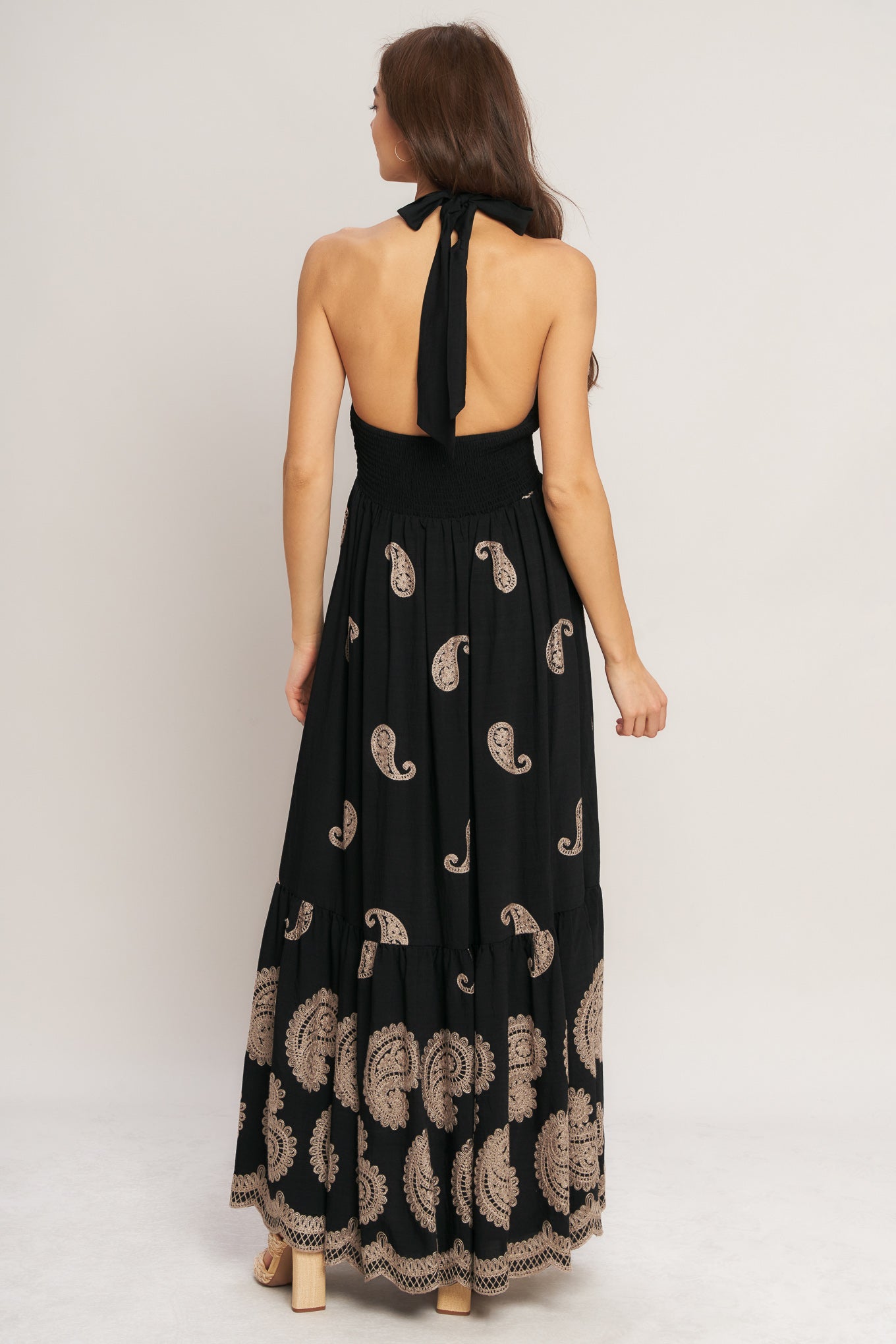An embroidered woven midi dress featuring halter neckline, smocked bodice with front tie and bare back with back neck tie closure