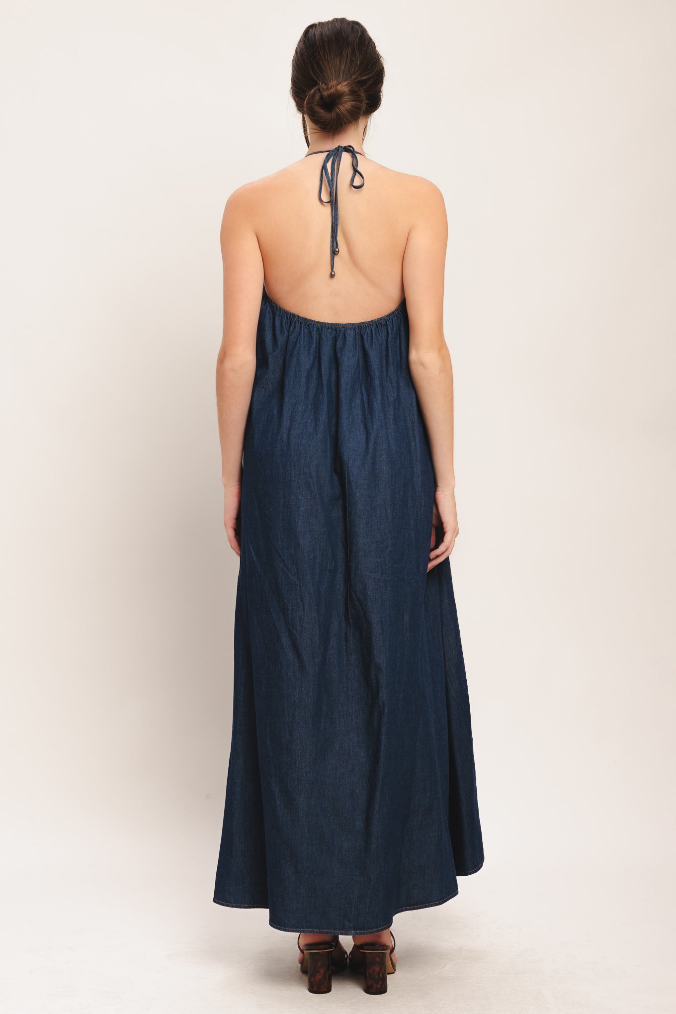 A solid denim midi dress featuring bib neckline and back neck tie and low back

Details:

Self: 100% Cotton

Size & Fit

-Model is 5`8" And Wearing Size Small
-Measurements Taken From Size Small
-Approx. Length: 53"