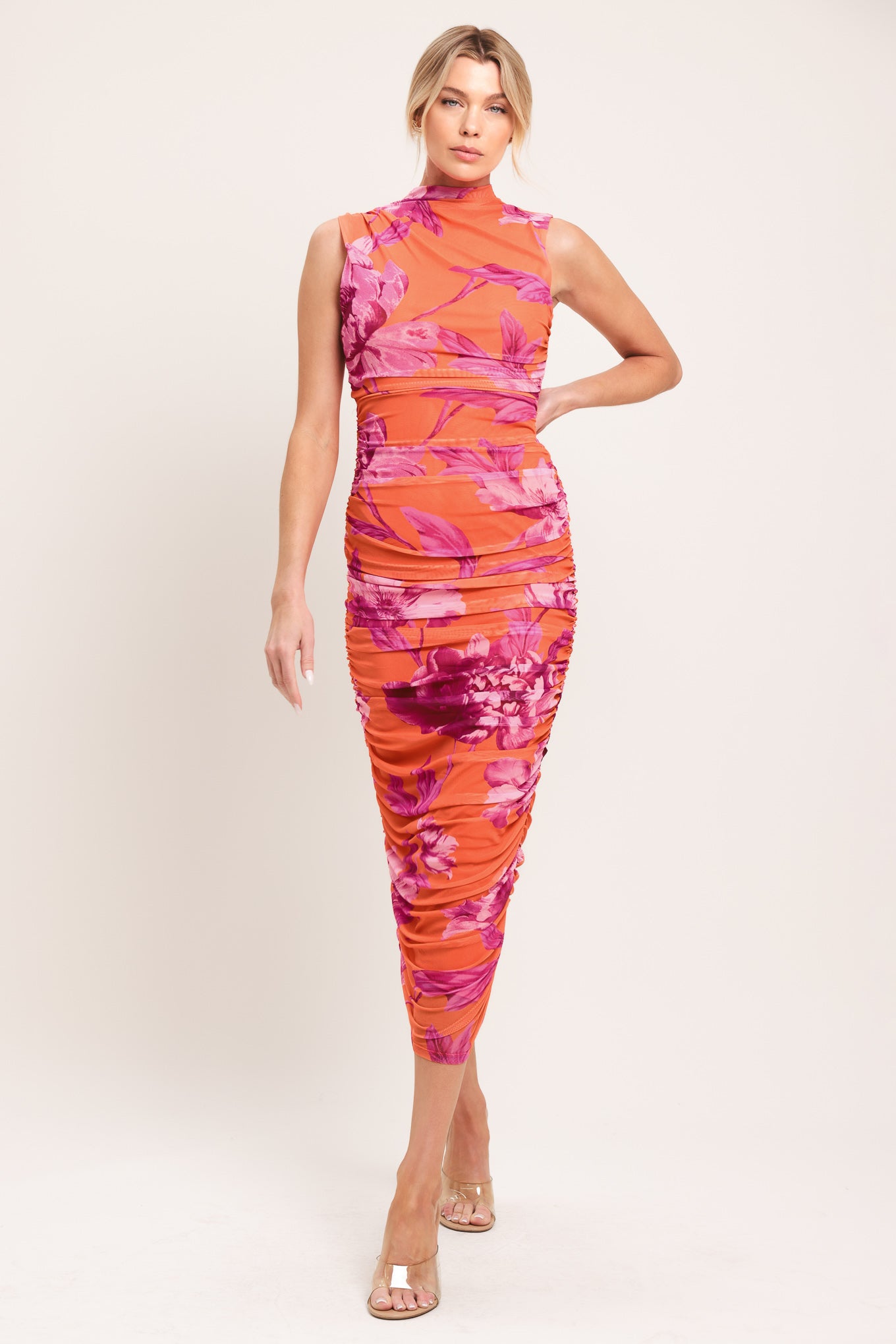 Woman wearing an orange and pink floral printed power mesh midi dress featuring tubular neckline, sleeveless and shirred body | Flying Tomato