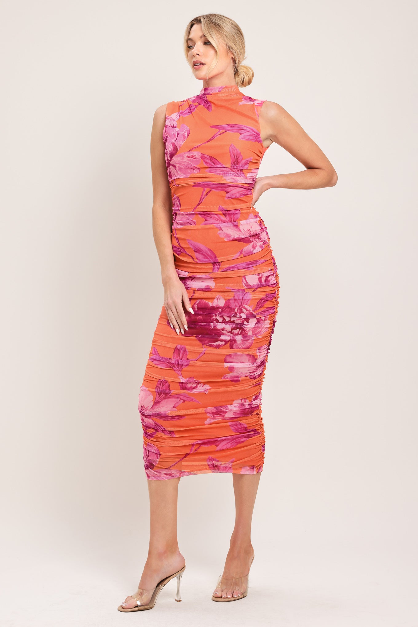 Woman wearing an orange and pink floral printed power mesh midi dress featuring tubular neckline, sleeveless and shirred body | Flying Tomato