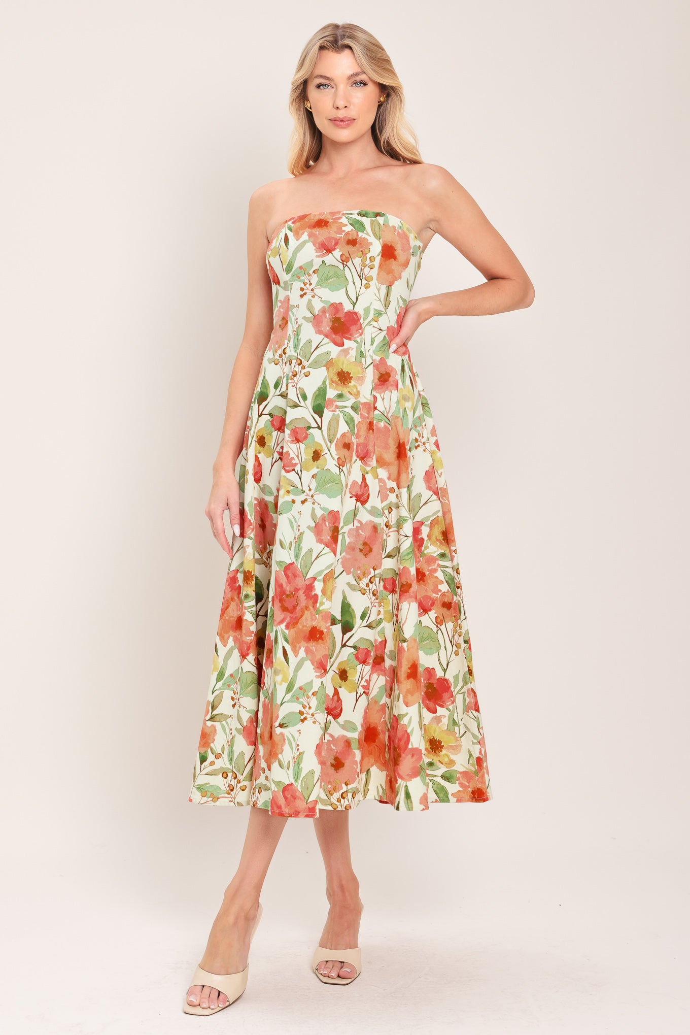 Woman wearing a strapless orange and green floral printed midi dress featuring  a circle skirt and back zipper closure | Flying Tomato
