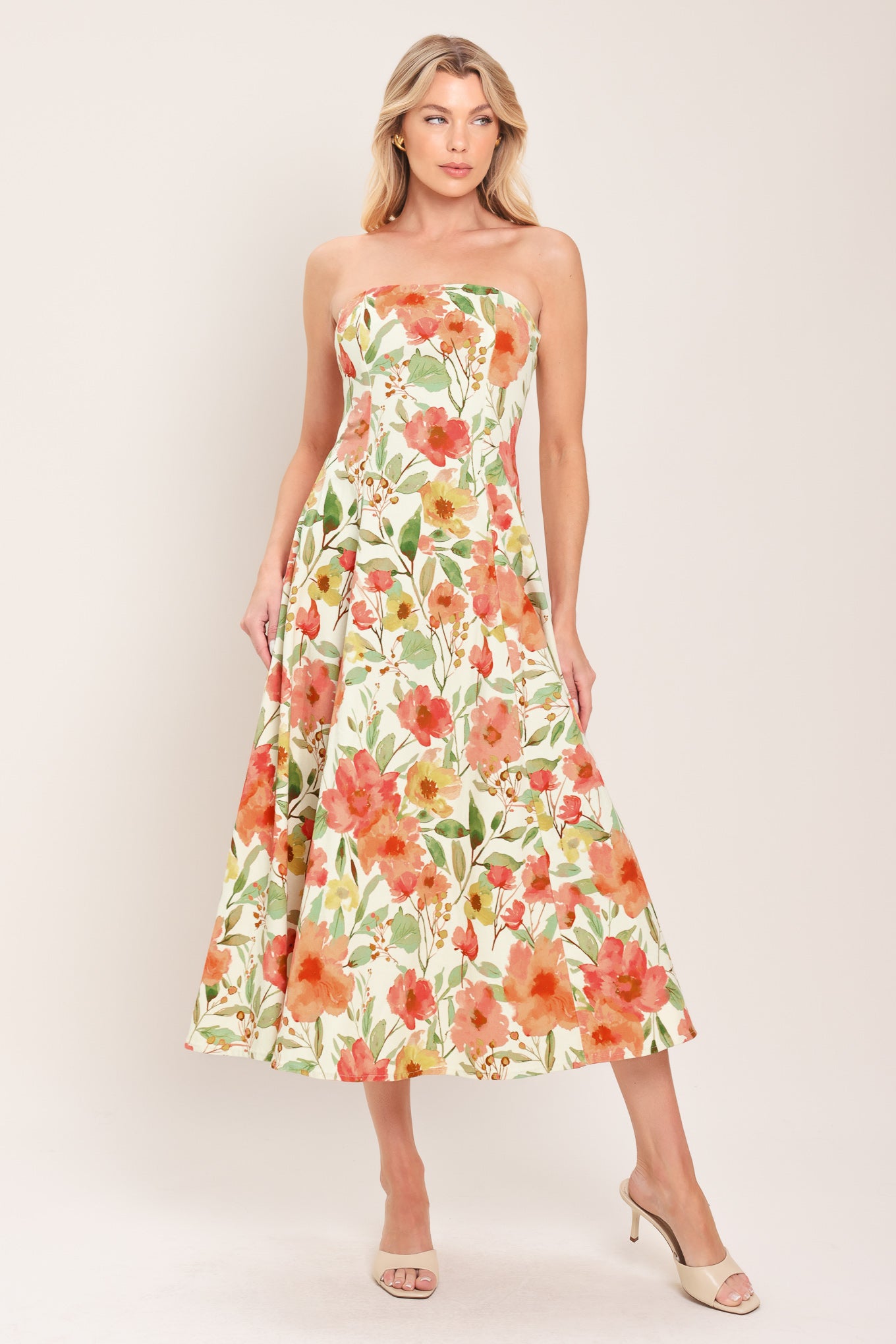 Woman wearing a strapless orange and green floral printed midi dress featuring  a circle skirt and back zipper closure | Flying Tomato
