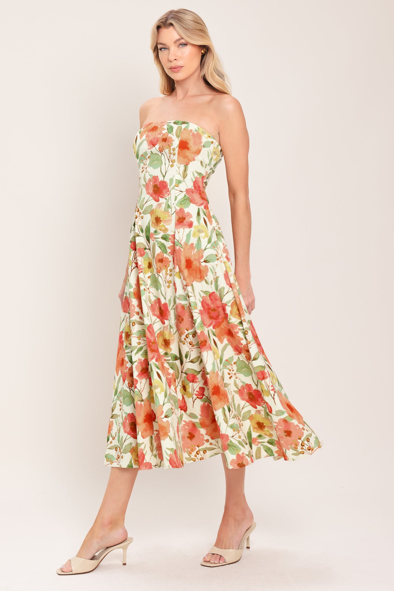 Woman wearing a strapless orange and green floral printed midi dress featuring  a circle skirt and back zipper closure | Flying Tomato