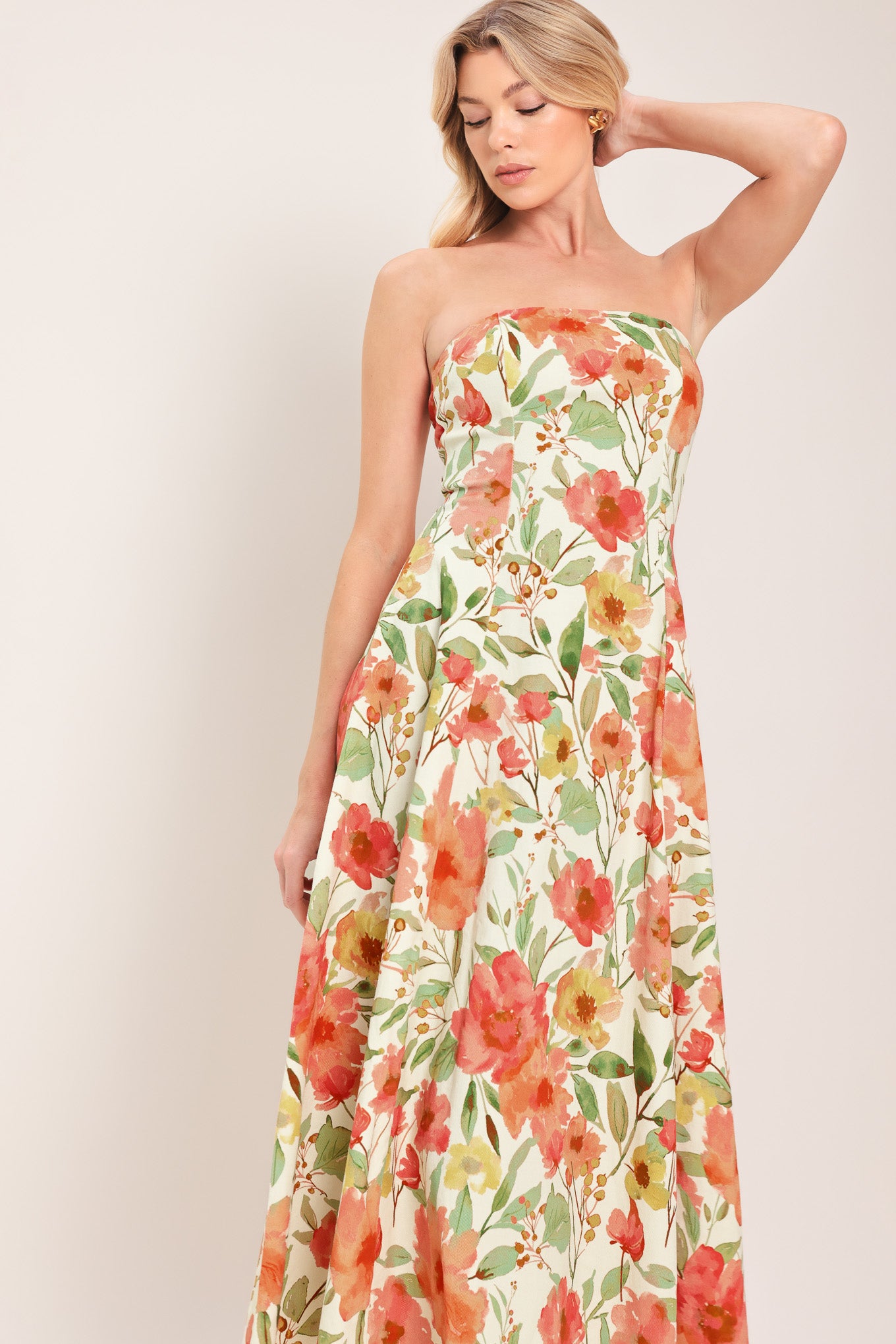 Woman wearing a strapless orange and green floral printed midi dress featuring  a circle skirt and back zipper closure | Flying Tomato