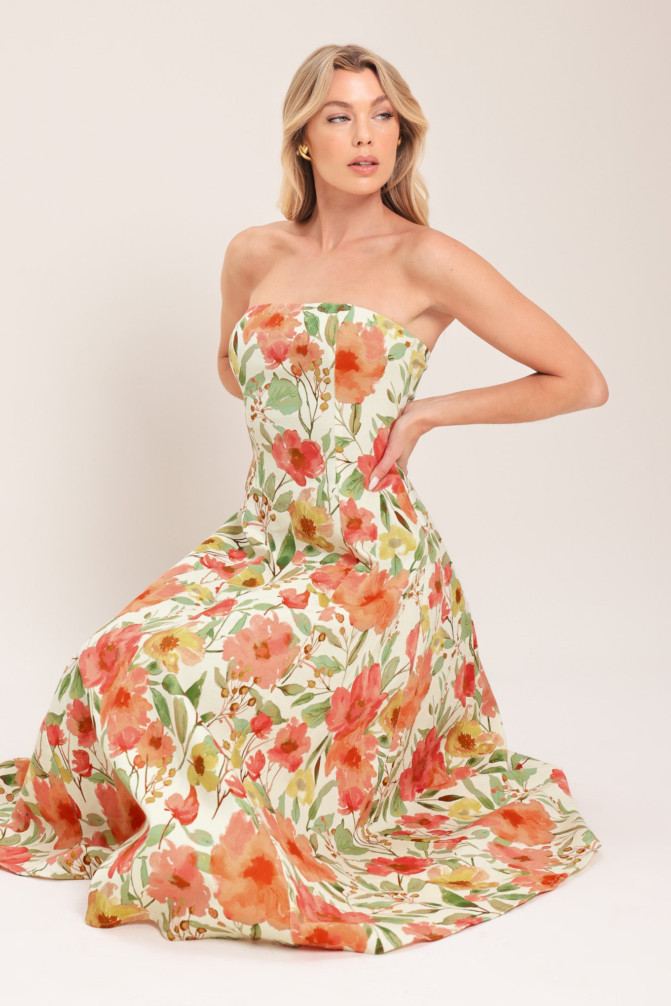 Woman wearing a strapless orange and green floral printed midi dress featuring  a circle skirt and back zipper closure | Flying Tomato