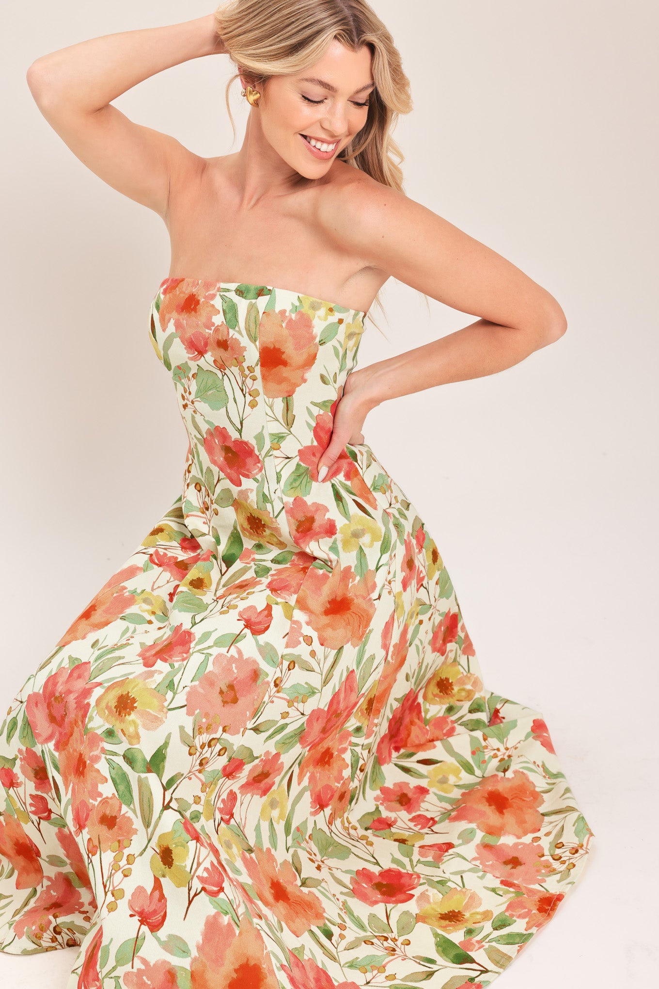 Woman wearing a strapless orange and green floral printed midi dress featuring  a circle skirt and back zipper closure | Flying Tomato