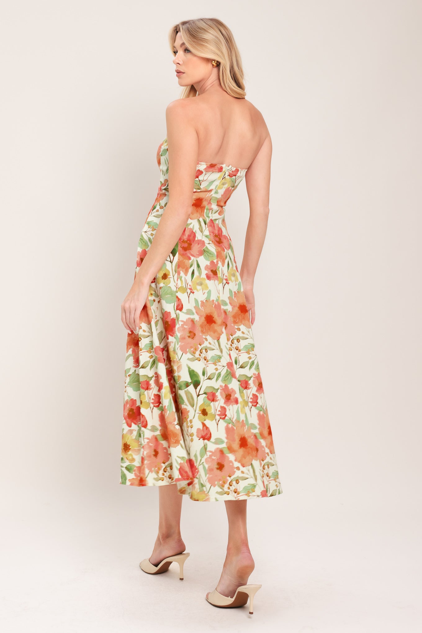 Woman wearing a strapless orange and green floral printed midi dress featuring  a circle skirt and back zipper closure | Flying Tomato