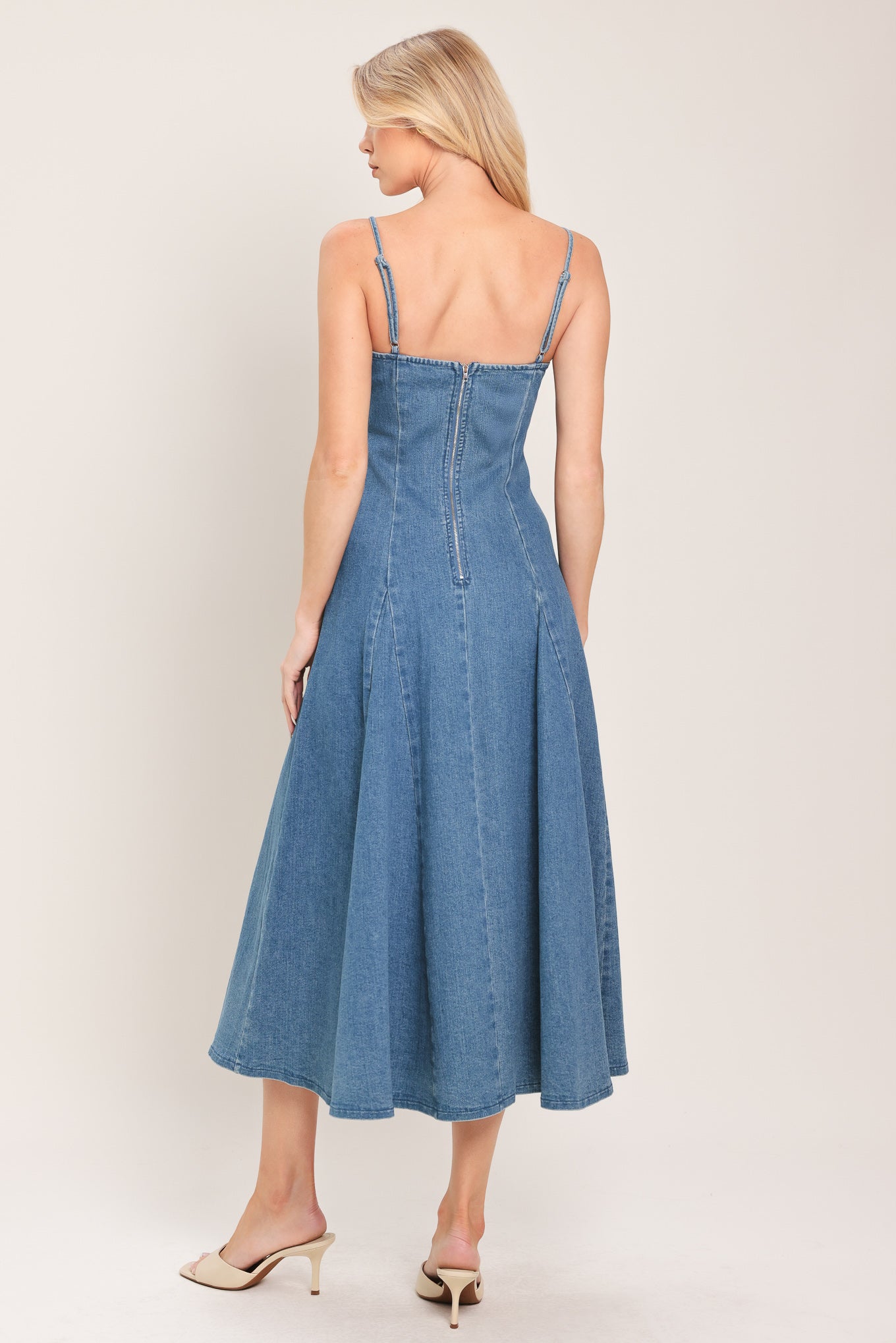 Woman wearing a denim midi dress featuring straight neckline, straps, full circle skirt and back zipper closure | Flying Tomato