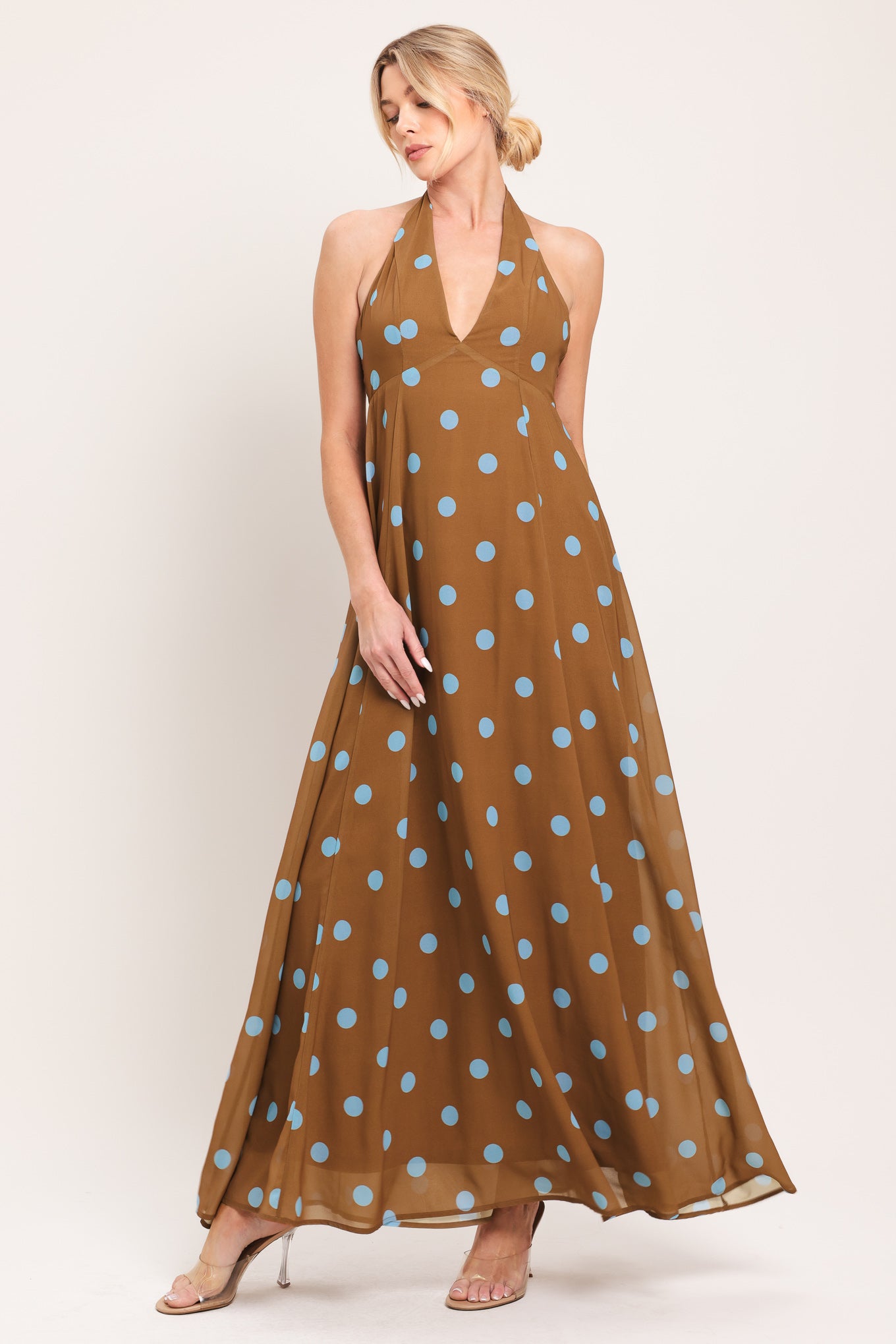 Woman wearing a brown with blue polka dots midi dress featuring halter neckline, circle skirt, bare back with tie neck and zipper closure | Flying Tomato