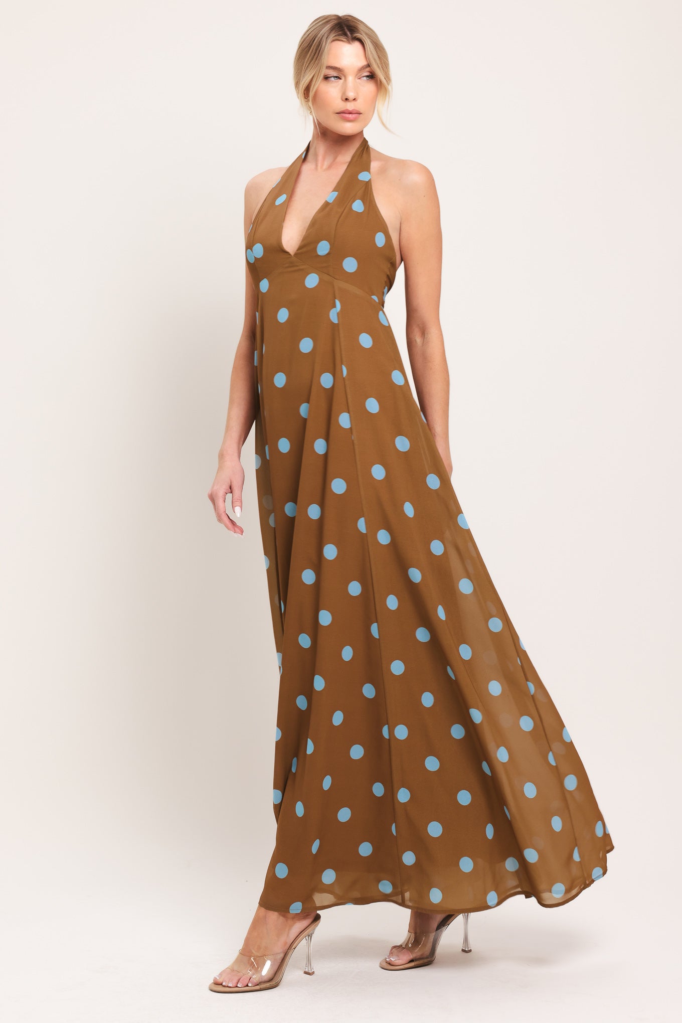 Woman wearing a brown with blue polka dots midi dress featuring halter neckline, circle skirt, bare back with tie neck and zipper closure | Flying Tomato