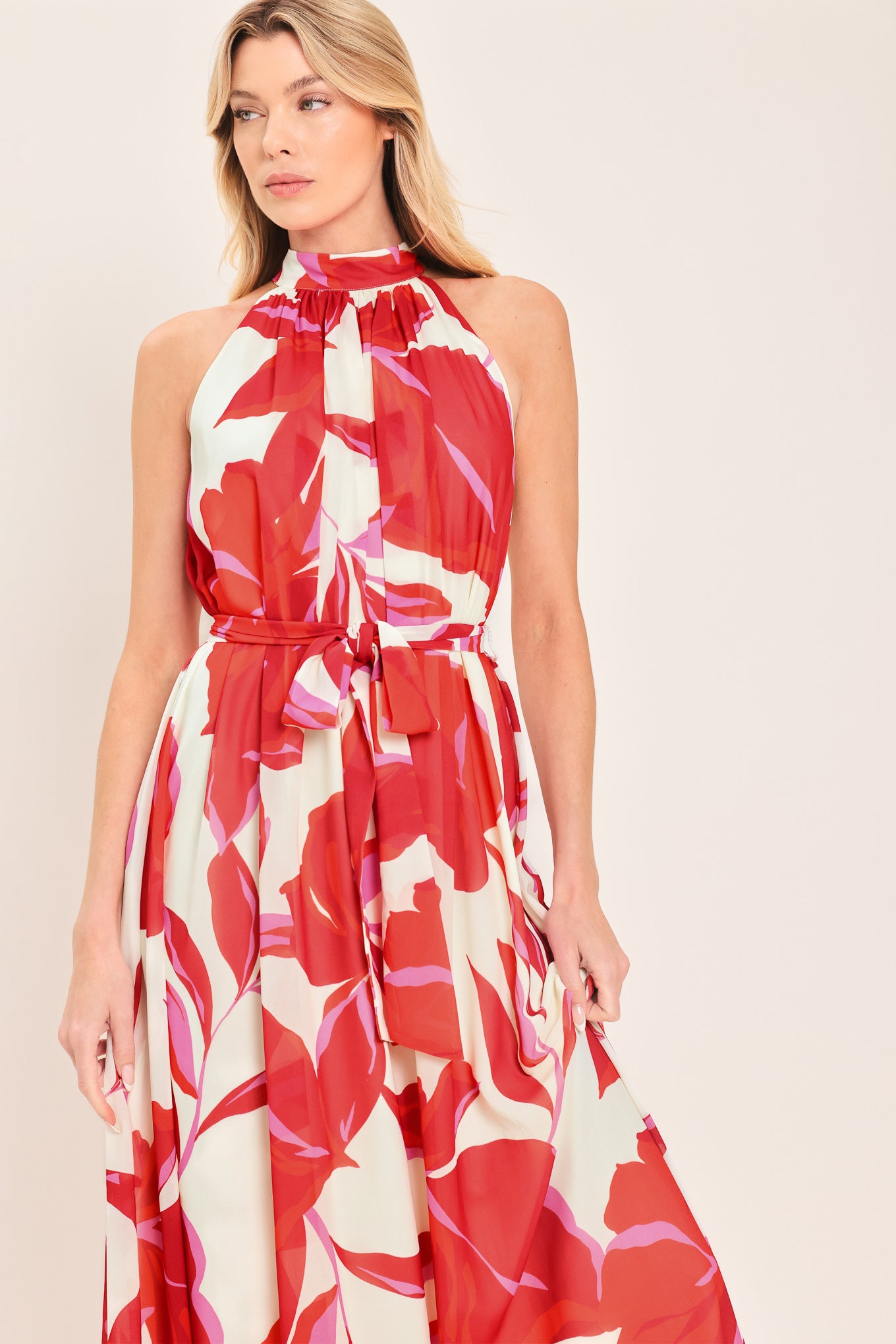 Woman wearing a red floral maxi dress with halter neckline, self sash tie and back button closure | Flying Tomato