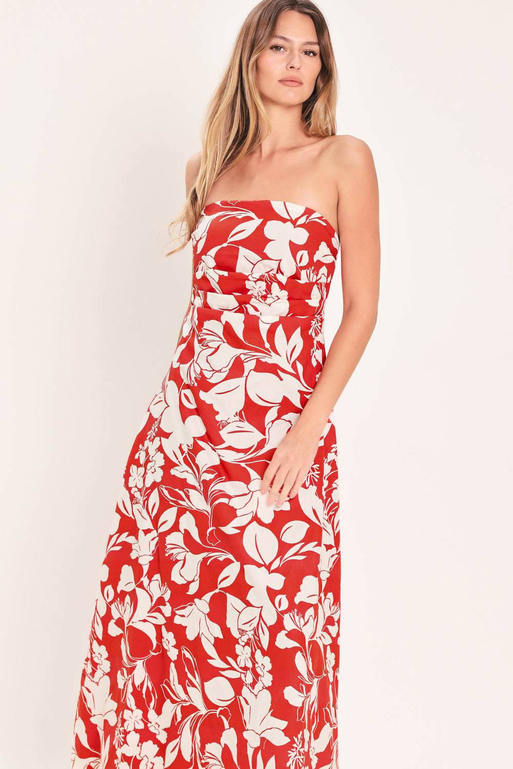 Woman wearing a red floral strapless midi dress featuring a circle skirt and back zipper closure | Flying Tomato