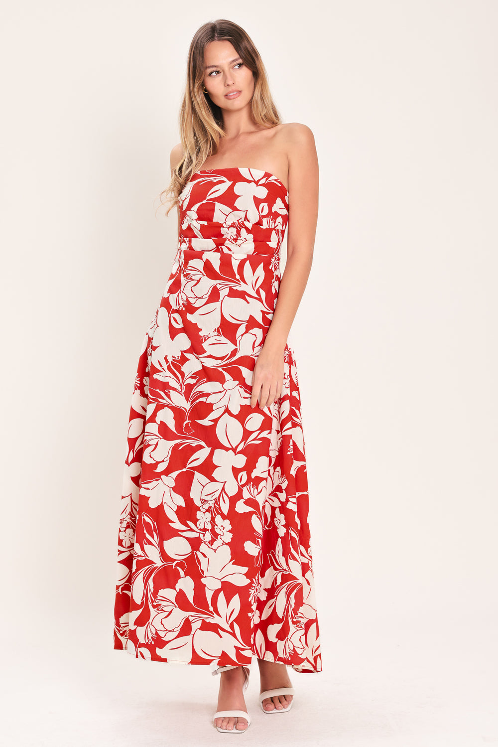 Woman wearing a red floral strapless midi dress featuring a circle skirt and back zipper closure | Flying Tomato
