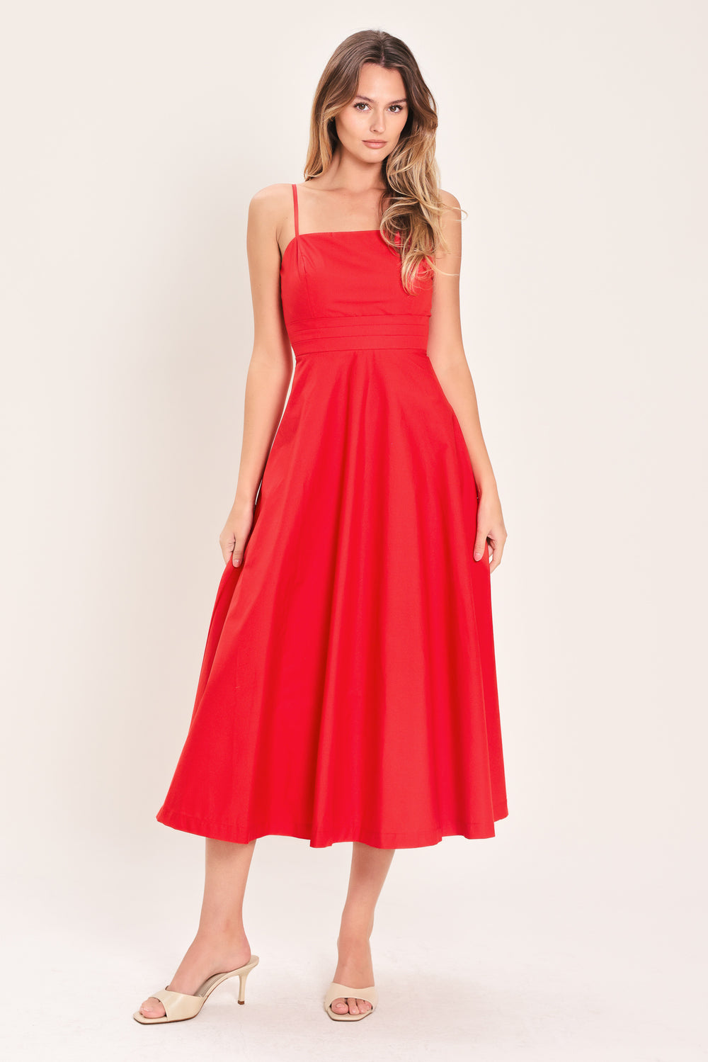 Woman wearing a red midi dress featuring straight neckline, straps, pleated waistband, circle skirt and back zipper closure | Flying Tomato