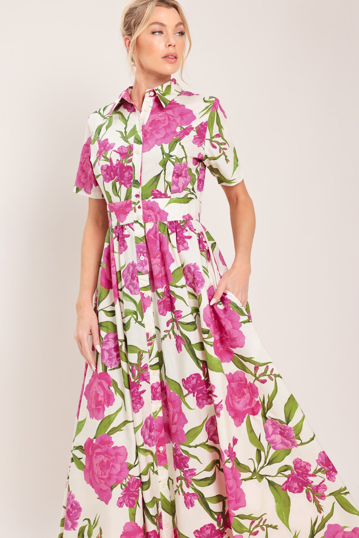 Woman wearing a short sleeve white shirt maxi dress wit pink floral print featuring front button down and full skirt | Flying Tomato